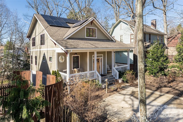 view of front of property with covered porch, a shingled roof, and solar panels