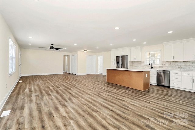 kitchen featuring light countertops, appliances with stainless steel finishes, open floor plan, white cabinetry, and a kitchen island