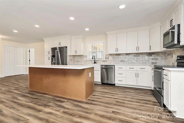 kitchen with stainless steel appliances, a center island, light countertops, and white cabinetry