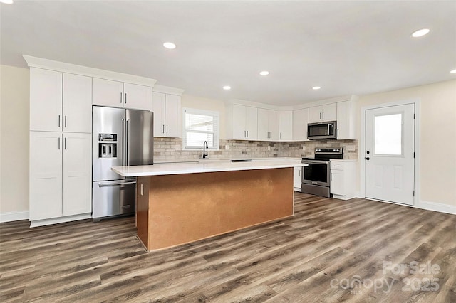 kitchen featuring a kitchen island, white cabinetry, light countertops, appliances with stainless steel finishes, and dark wood finished floors