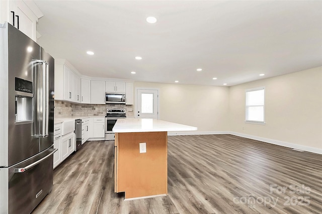 kitchen featuring a center island, tasteful backsplash, light countertops, appliances with stainless steel finishes, and white cabinetry