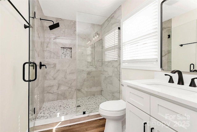 bathroom featuring toilet, wood finished floors, vanity, and a shower stall