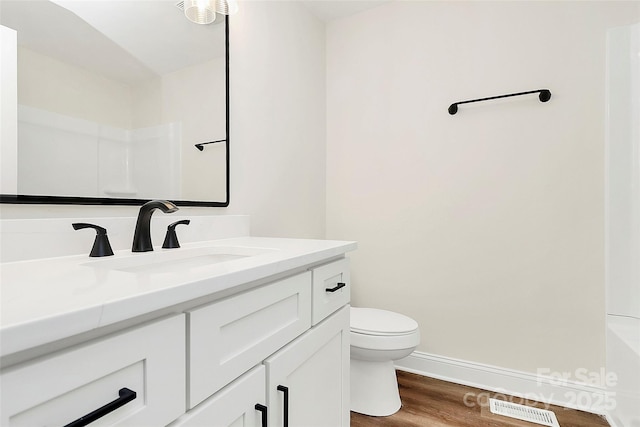 bathroom featuring visible vents, toilet, vanity, wood finished floors, and baseboards