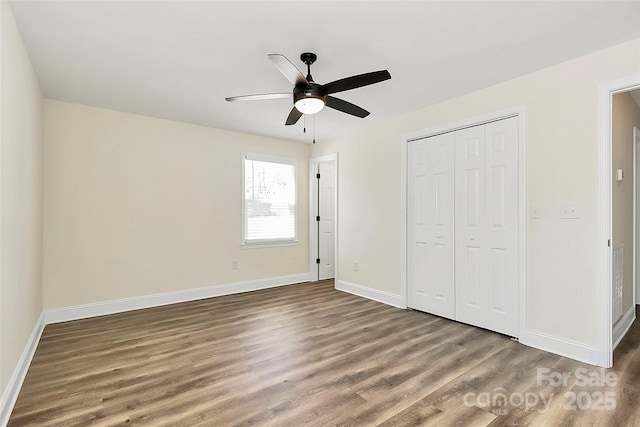 unfurnished bedroom with dark wood-style floors, a closet, ceiling fan, and baseboards