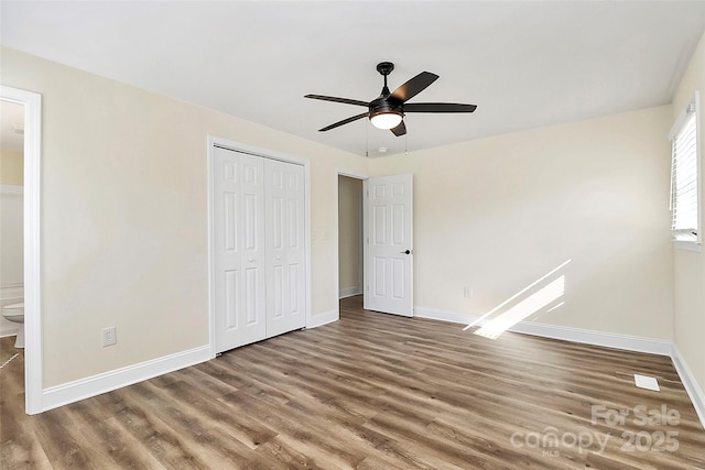 unfurnished bedroom featuring a closet, wood finished floors, and baseboards