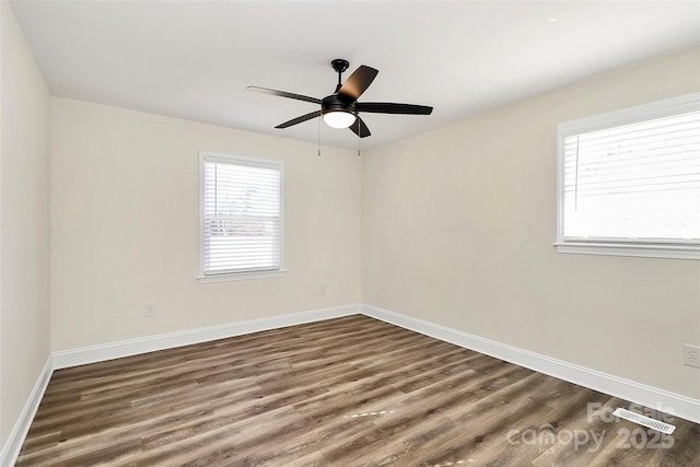 spare room featuring visible vents, dark wood finished floors, baseboards, and ceiling fan