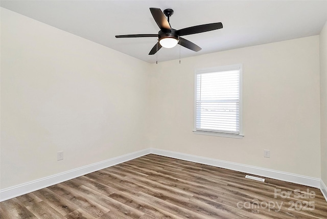 unfurnished room featuring a ceiling fan, visible vents, baseboards, and wood finished floors