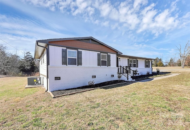 view of front of home with board and batten siding, cooling unit, crawl space, and a front lawn