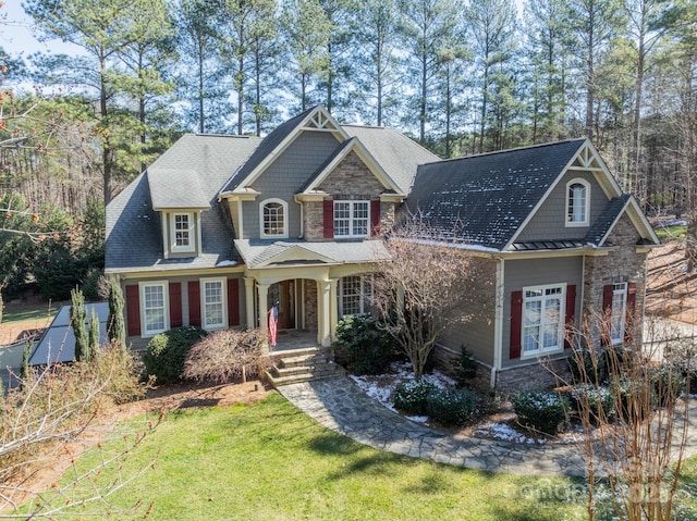 craftsman inspired home featuring stone siding, a porch, and a front lawn