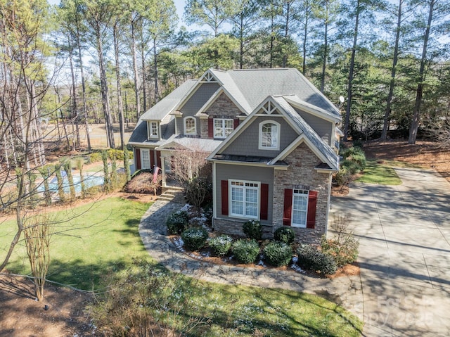 craftsman-style house with stone siding and a front yard