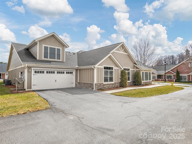 view of front of property with central AC unit, a front yard, and a garage