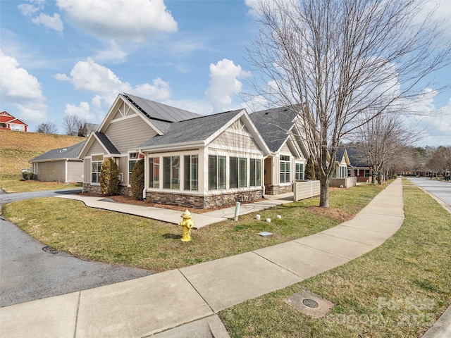 craftsman house featuring a front lawn, solar panels, and a sunroom