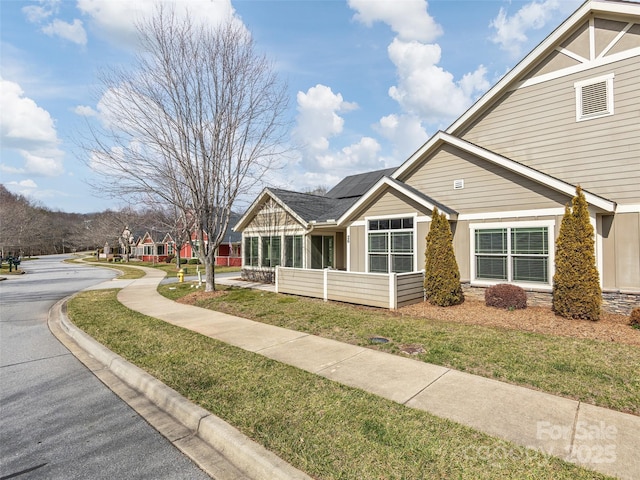 view of front of home with solar panels and a front yard