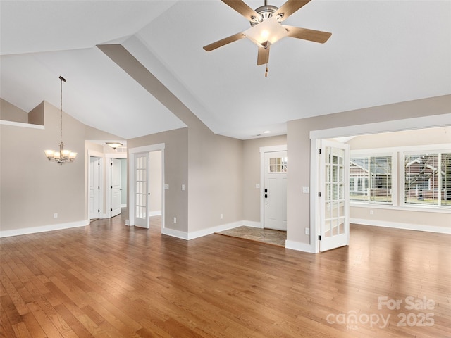 unfurnished living room with high vaulted ceiling, hardwood / wood-style flooring, ceiling fan with notable chandelier, and french doors