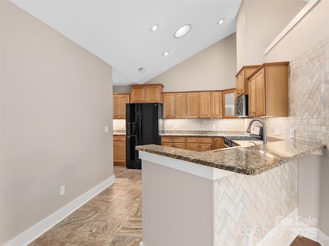 kitchen featuring dark stone counters, a breakfast bar area, kitchen peninsula, appliances with stainless steel finishes, and decorative backsplash