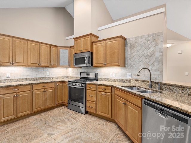 kitchen featuring high vaulted ceiling, stainless steel appliances, decorative backsplash, light stone countertops, and sink