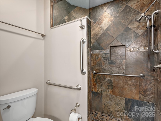 bathroom with a tile shower and toilet