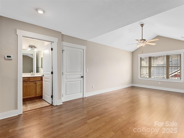 empty room featuring sink, ceiling fan, hardwood / wood-style floors, and vaulted ceiling