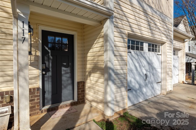 entrance to property featuring a garage and brick siding