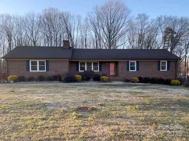 ranch-style home featuring brick siding, a chimney, and a front yard