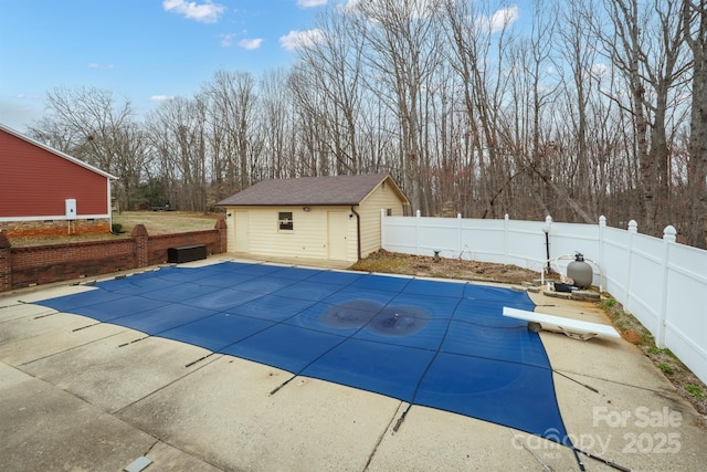 view of swimming pool featuring a diving board, an outdoor structure, a fenced backyard, and a fenced in pool