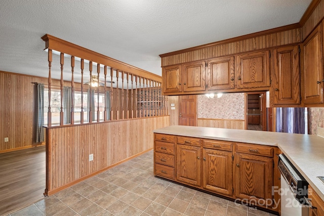 kitchen with a textured ceiling, white dishwasher, brown cabinetry, and light countertops