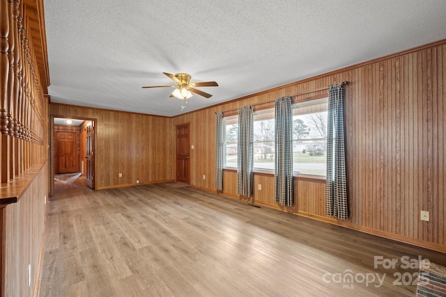 unfurnished room featuring light wood-style floors, crown molding, and a textured ceiling