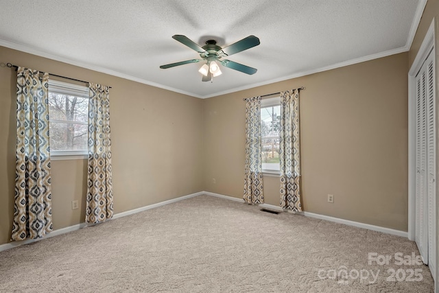 unfurnished bedroom with a textured ceiling, carpet floors, a closet, and crown molding