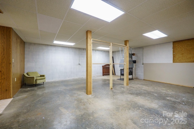 finished basement featuring concrete block wall and a drop ceiling