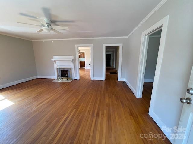 unfurnished living room with ceiling fan, dark hardwood / wood-style flooring, and ornamental molding