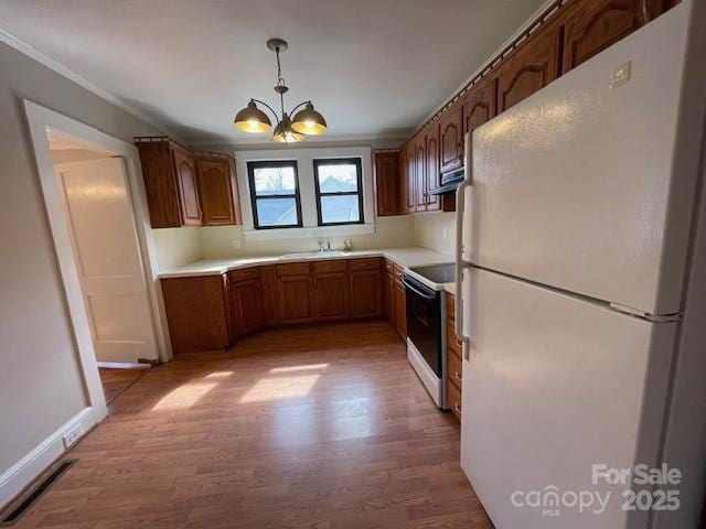 kitchen with light wood-type flooring, electric range, white refrigerator, sink, and pendant lighting