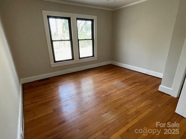 empty room with wood-type flooring and crown molding