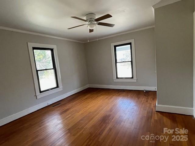 empty room with ceiling fan, ornamental molding, dark hardwood / wood-style floors, and plenty of natural light