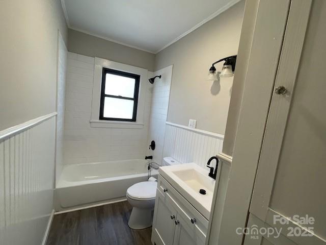 full bathroom featuring hardwood / wood-style flooring, toilet, tiled shower / bath, vanity, and crown molding