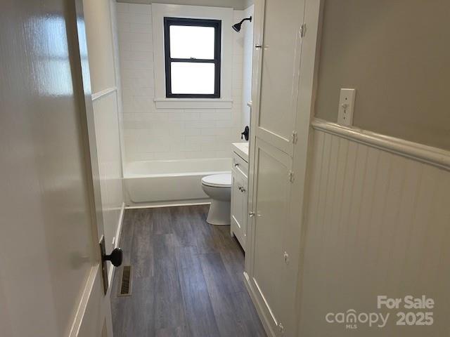 full bathroom featuring toilet, hardwood / wood-style flooring, tiled shower / bath, and vanity