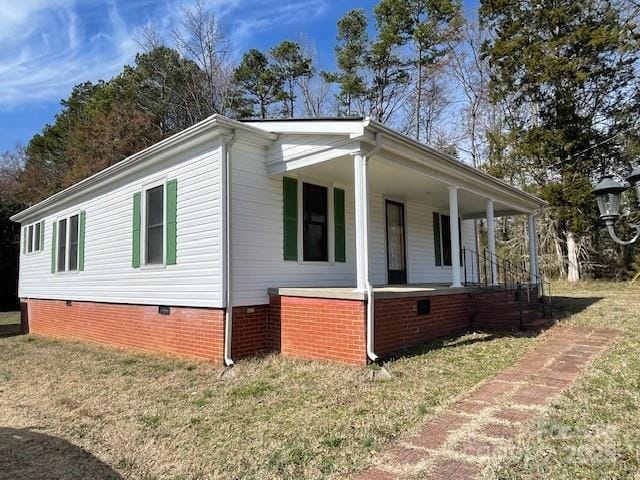 view of side of home with covered porch and a yard