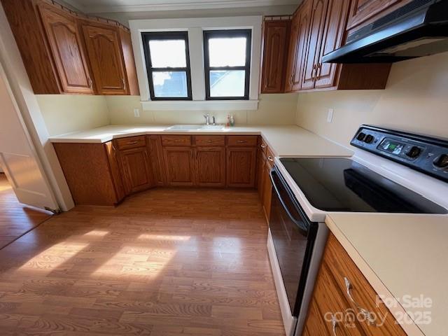 5135 Tucker Ave, Kannapolis, NC 28081 - kitchen with extractor fan, electric range oven, light wood-style flooring, and brown cabinetry