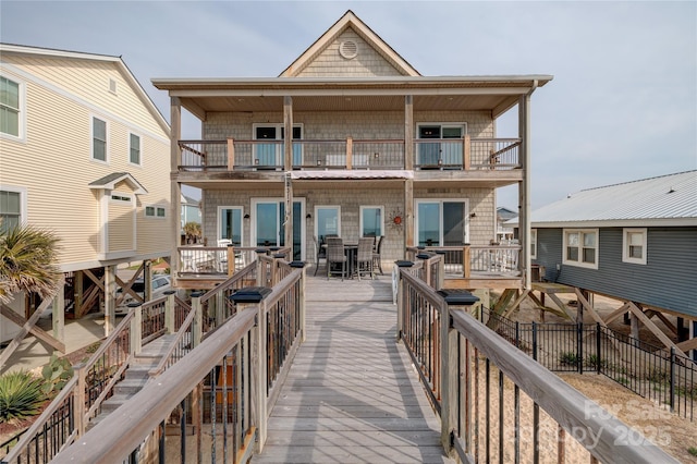 rear view of property with outdoor dining area and a balcony
