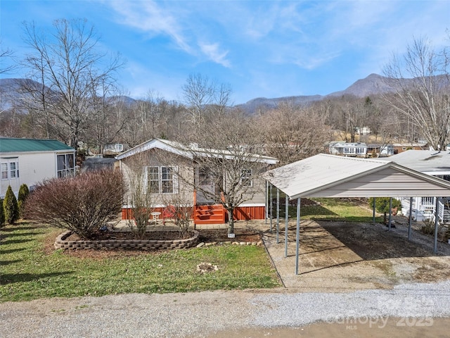 view of front of property with a mountain view, a front lawn, and a carport