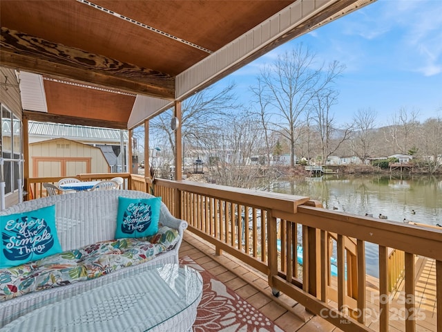 wooden terrace featuring a water view and a shed