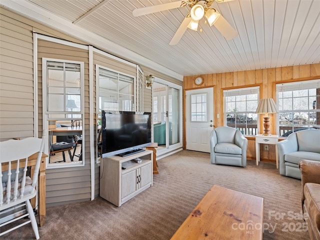 carpeted living room with wood ceiling, wooden walls, and ceiling fan