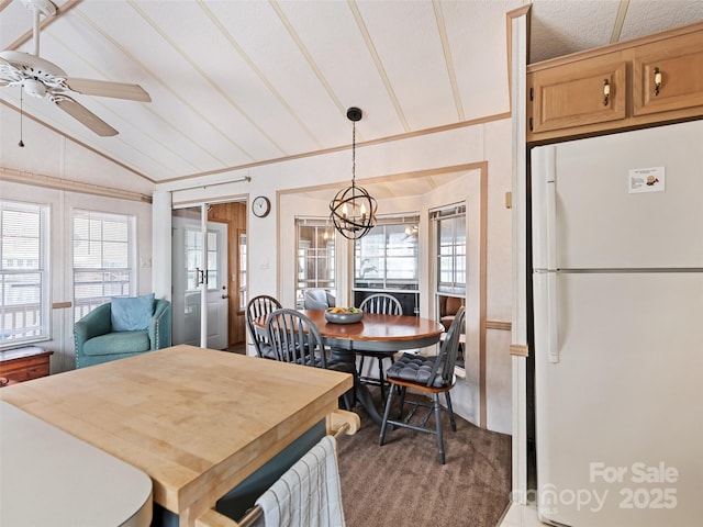 dining space with vaulted ceiling, plenty of natural light, and ceiling fan with notable chandelier