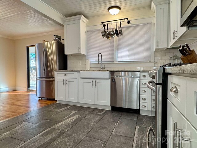 kitchen with a sink, stainless steel appliances, white cabinets, crown molding, and tasteful backsplash