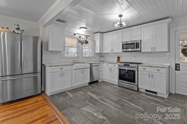 kitchen featuring a notable chandelier, ornamental molding, white cabinetry, stainless steel appliances, and decorative backsplash