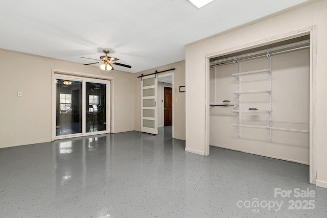 interior space with ceiling fan and a barn door