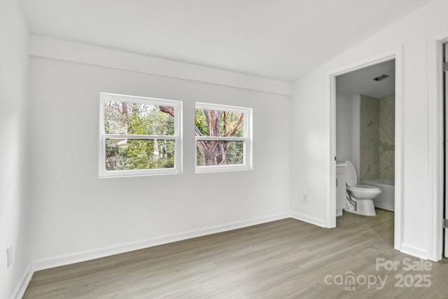 unfurnished bedroom featuring hardwood / wood-style floors and connected bathroom