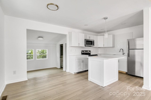 kitchen featuring white cabinetry, stainless steel appliances, light hardwood / wood-style flooring, decorative light fixtures, and a kitchen island