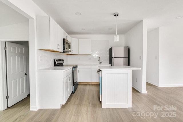 kitchen with appliances with stainless steel finishes, a center island, white cabinetry, hanging light fixtures, and tasteful backsplash