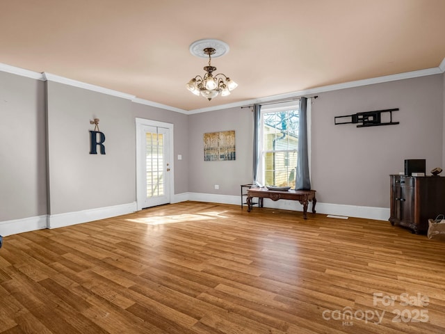 entryway featuring ornamental molding, a chandelier, light wood-style flooring, and baseboards