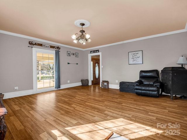 sitting room with light wood-type flooring, baseboards, a chandelier, and crown molding